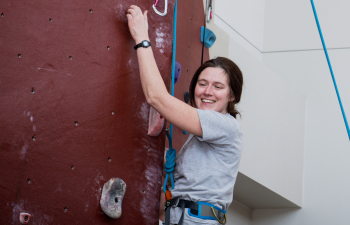 Student ascends the rock climbing wall in the Falcon Center